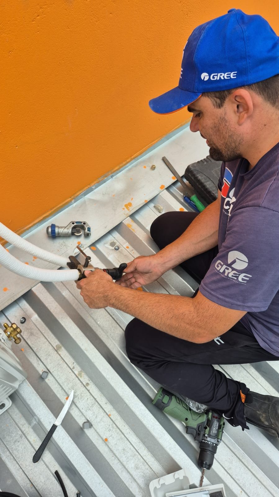 Charles realizando serviço técnico em uma instalação de ar-condicionado